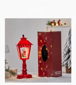 Détail d'une lanterne de Noël rouge avec décor de Père Noël et sa boîte cadeau assortie
