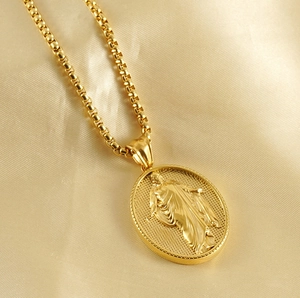 Macro detail of a 18k gold religious relief pendant on soft satin fabric texture