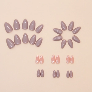 Almond-shaped press-on nails in mauve and pink with delicate white floral patterns