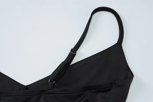 Detail of adjustable metal buckle and stitching on black mesh spaghetti strap dress