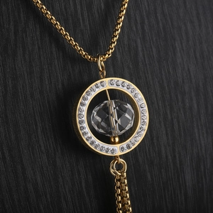 Detailed macro view of a gold circle sweater necklace featuring a large faceted crystal
