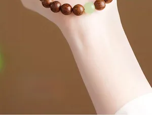 Macro detail of natural wood prayer beads with a single light green jade accent stone