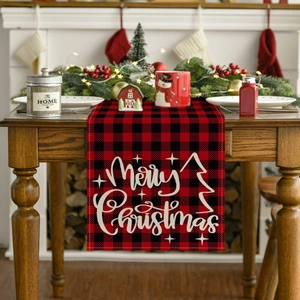 Classic red and black plaid Christmas table runner with Merry Christmas text on a wooden table