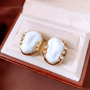 Detail of vintage oval resin earrings with gold pleated texture and rhinestones