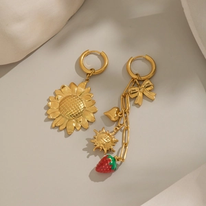 Detailed shot of asymmetric sunflower and strawberry earrings with heart and bow charms