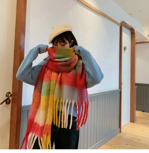 Detail of colorful rainbow plaid mohair scarf with soft long fringes worn with beige beret