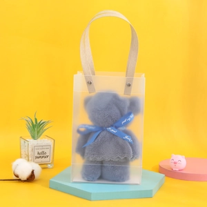 Blue bear-shaped towel gift set in a transparent bag with handle on yellow backdrop
