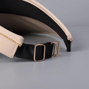 Détail d'un chapeau de soleil en raphia avec bande élastique noire et boucle dorée réglable