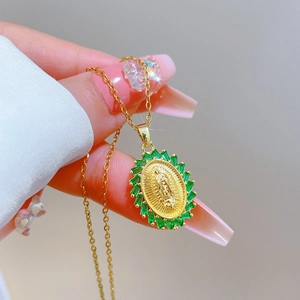 Detail of gold oval pendant featuring Virgin Mary relief and green baguette crystals