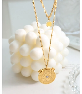 Detail of double-layer gold starburst necklace with round compass pendant and crystal