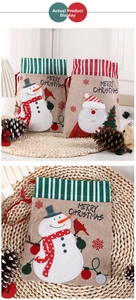 Close-up of linen Christmas drawstring gift bags featuring Santa and snowman patterns