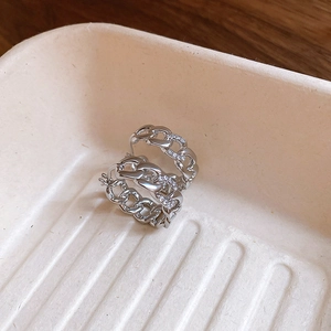 Detailed view of silver Cuban link hoop earrings with sparkling cubic zirconia on wood