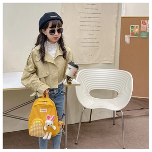 Toddler yellow backpack with cute white rabbit doll and checkered pocket on a girl