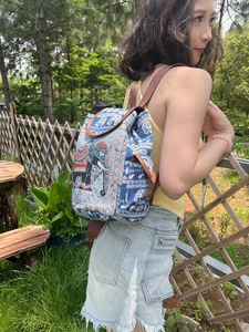 Detail view of ethnic embroidery elephant pattern on blue canvas backpack with leather flap