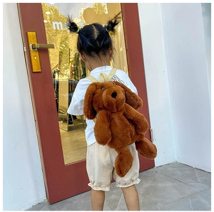 Outdoor shot of a toddler wearing a soft brown plush dog backpack with beige straps