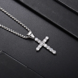 Detailed view of silver cross pendant with cubic zirconia stones and box chain style