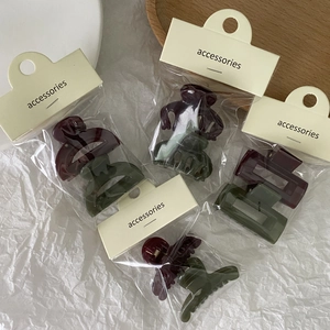 Detailed view of mini jelly hair claws in burgundy and olive green in clear packaging