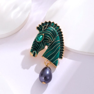 Macro view of zebra brooch with green enamel, gold trim and purple pearl pendant