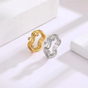 Macro detail of wave-shaped stainless steel rings in gold and silver with cubic zirconia
