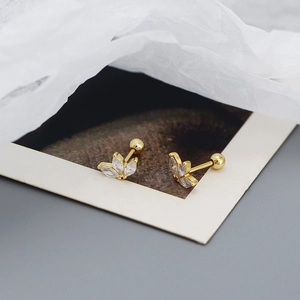 Close-up of gold clover stud earrings with sparkling cubic zirconia on white tissue paper