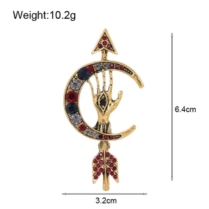 Detailed size view of a vintage crescent moon and hamsa hand brooch with crystals