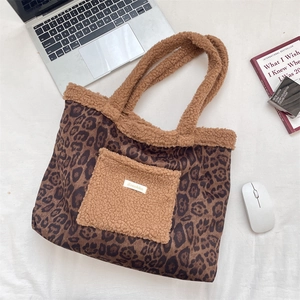 Flat lay of leopard print tote bag with plush pockets beside a laptop and books