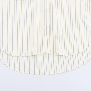 Detail view of a striped cotton shirt showing curved hem and precision stitching quality