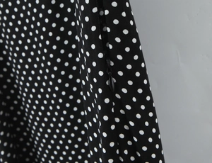 Detail of hidden side zipper on black polka dot dress with premium fabric texture