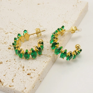Detalle macro de pendientes de aro en oro de 18K con circonitas verdes en piedra beige