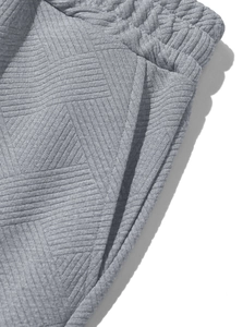 Détail du pantalon de jogging gris avec texture géométrique et couture de taille élastique