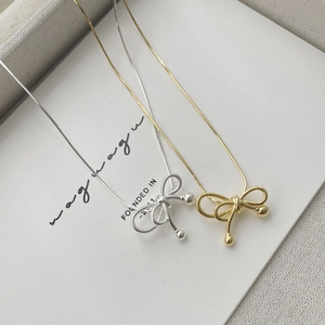 Detailed macro view of S925 silver bow pendant necklace in gold and silver finishes