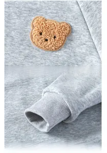 Detail of grey kids sweatshirt showing brown plush bear patch and ribbed cuffs