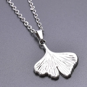 Macro detail of silver ginkgo leaf pendant showing intricate vein texture on a matte background