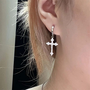 Silver cross earrings with clear rhinestones worn by a model in a close-up profile view