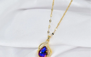 Close-up of golden teardrop necklace with violet-blue crystal and white gemstones