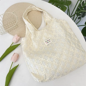 Close-up of cream white lace texture tote bag with 3D floral pattern and brand label