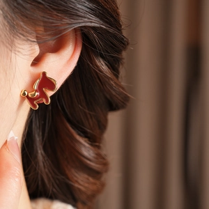 Close-up of a model wearing a gold-plated red puppy earring with elegant pearl accents