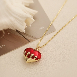 Vista dettagliata della collana con cuore rosso e design a goccia d'oro su sfondo