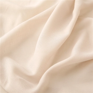 Detalle de la textura suave y los pliegues naturales de una bufanda de lino color crema