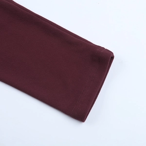 Détail macro d'une manche de robe bordeaux avec double couture et texture brossée douce