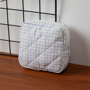 Close-up of quilted floral cosmetic bag with white zipper and metal pull ring