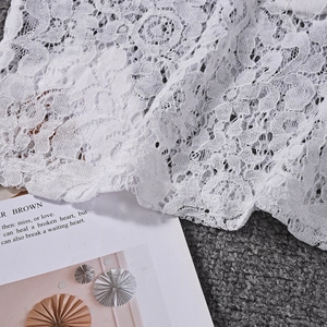 Detail of white floral lace fabric featuring intricate hollowed patterns and fine embroidery