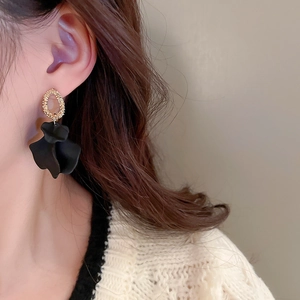 Close-up of a model wearing a gold ring earring with a vintage black flower pendant