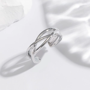 Dettaglio dell'anello in rame argento con linee irregolari intrecciate e finitura lucida