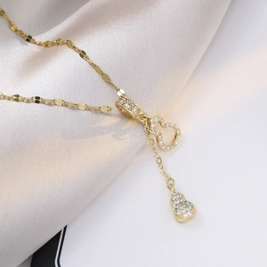 Macro detail of gold double gourd pendants with sparkling pavé crystals on a textured chain