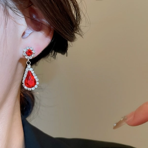Detail of elegant red teardrop earrings with crystals worn by a model in a close-up shot
