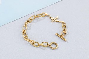 Macro detail of gold OT toggle clasp and ECG lifeline pattern on chunky metal chain