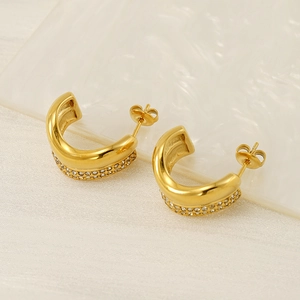 Detailed view of C-shaped gold earrings featuring double-row zircon inlay and butterfly backs