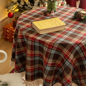 Round red and green Christmas plaid tablecloth with fringe in a cozy festive scene