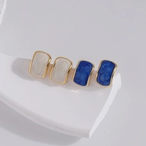 Rectangular enamel earrings in cream and blue with gold borders on minimalist stands